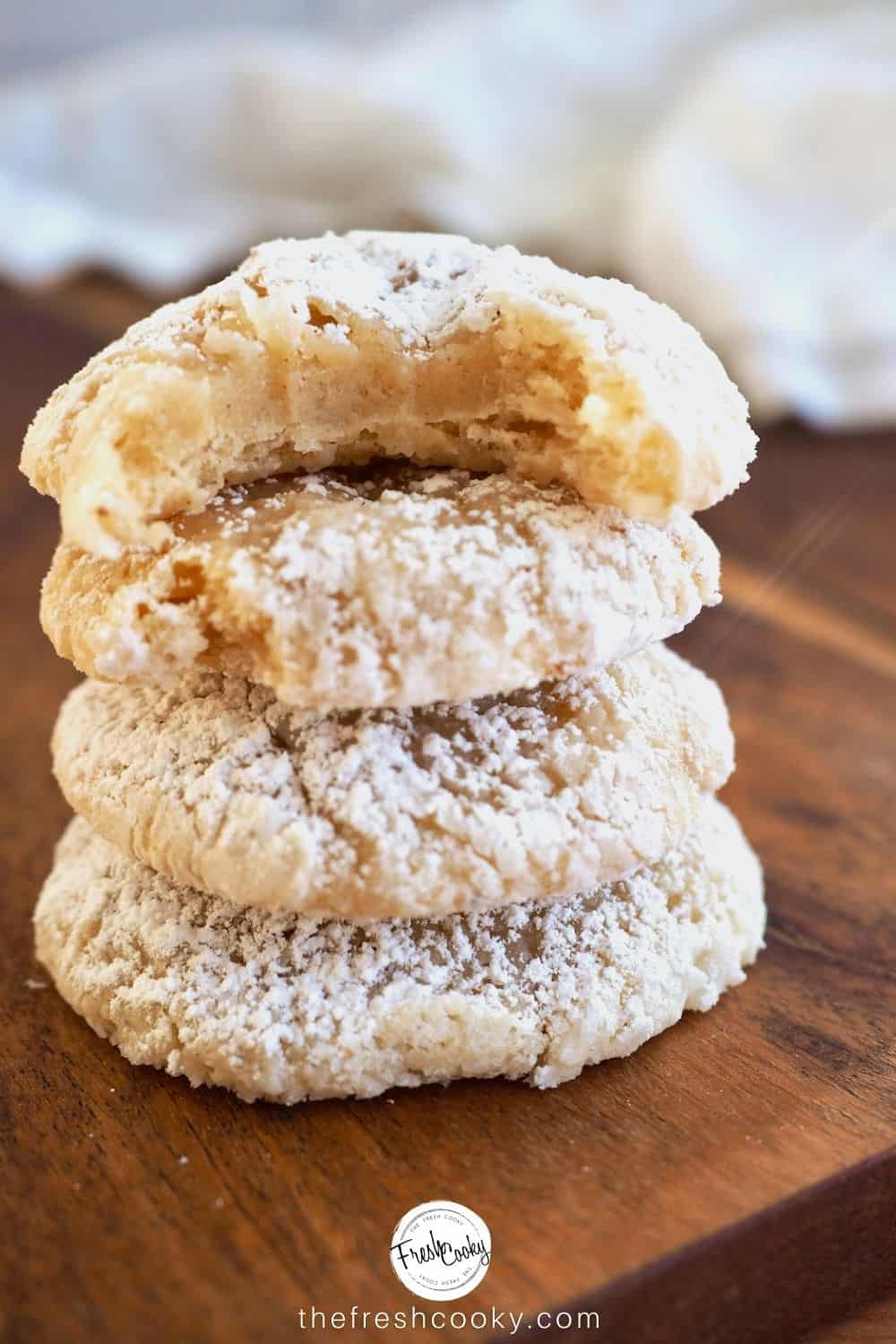 four eggnog butter cookies stacked one with bite of it.