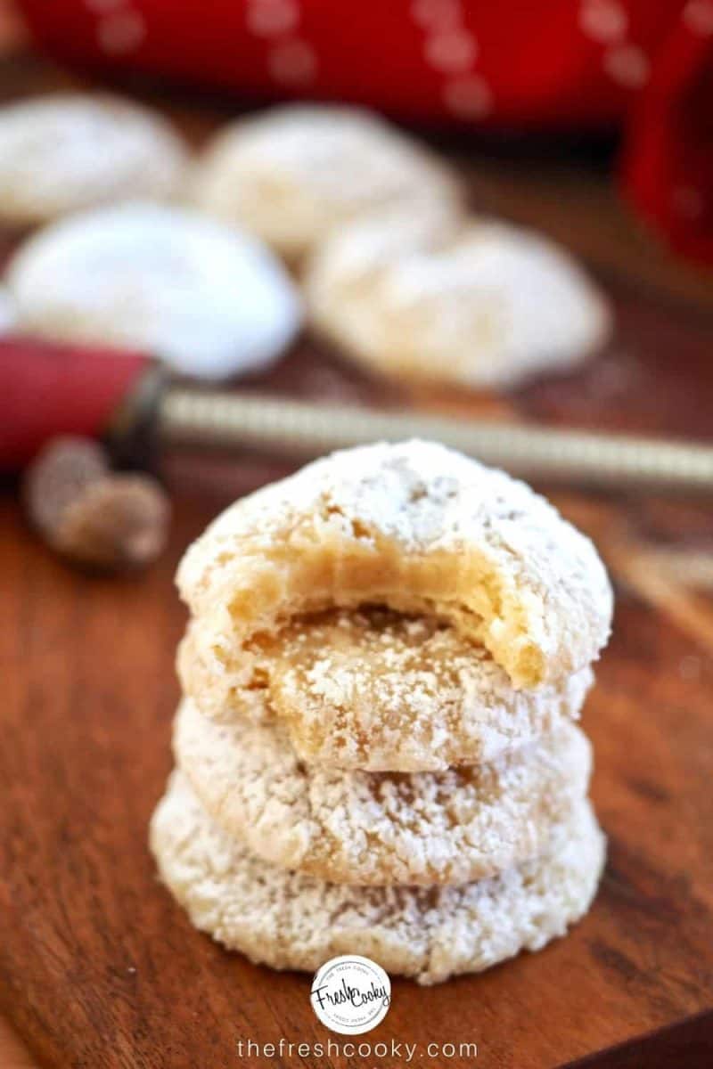 IMAGE of stack of eggnog gooey butter cookies with bite taken out of it. with nutmeg and spice grater in background.