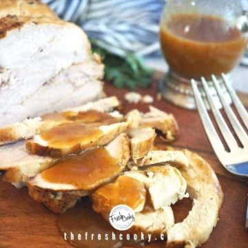 Facebook image of Sliced Turkey Breast on cutting board with pan gravy drizzled on top. Large fork in foreground with pitcher of gravy behind.