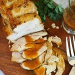 Top down shot of cooked Instant Pot Turkey Breast drizzled with pan gravy, on wooden cutting board.