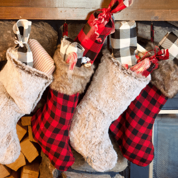 Square image of stockings hung on a fireplace mantle, stuffed with gifts.