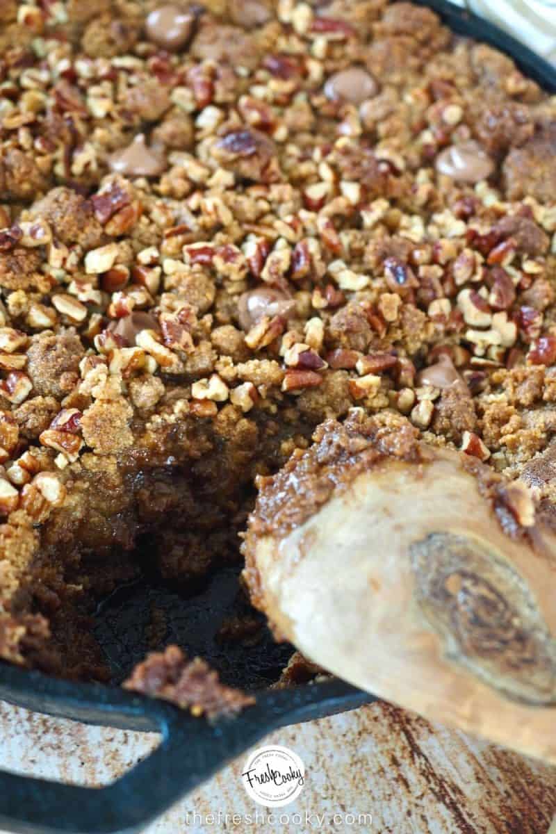 Wooden spoon with scoop out of chocolate crisp skillet dessert