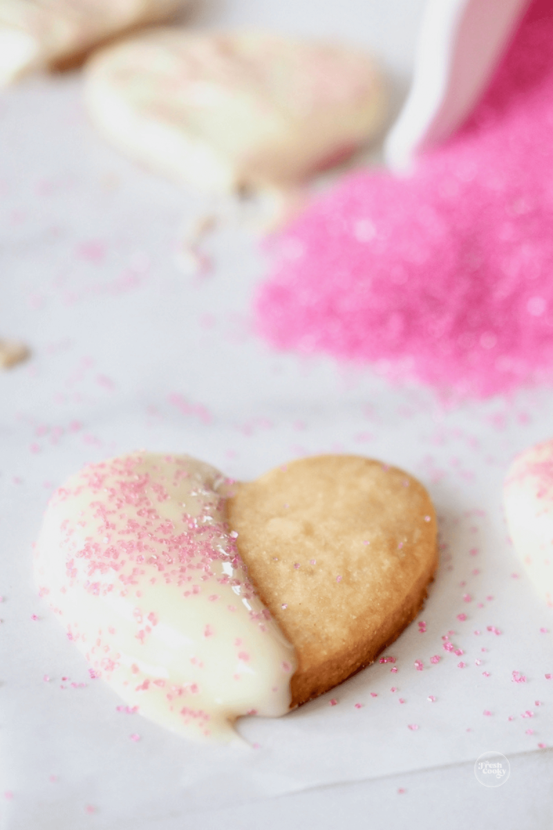 Heart-shaped cookie cutter shortbread cookie dipped in white chocolate with sprinkles.