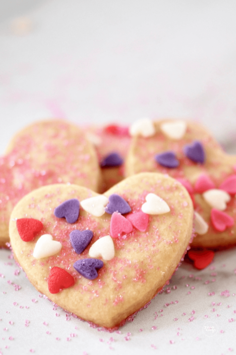 Heart-shaped shortbread cookies sprinkled with colored sugar and candy hearts.