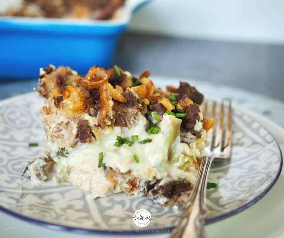 Serving of leftover turkey divan on a pretty patterned gray plate with a silver fork and blue casserole dish in background.