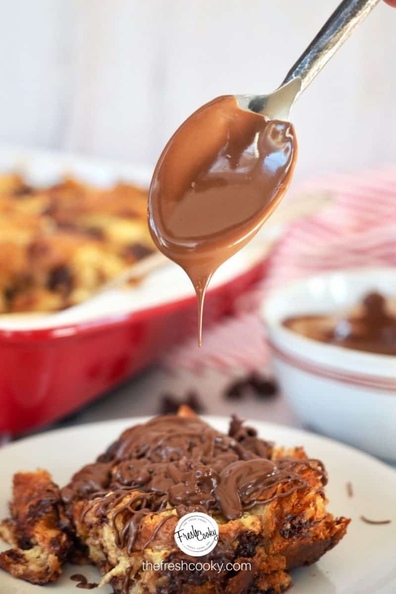 Square of Chocolate Chip Croissant French Toast with spoon drizzling nutella on top