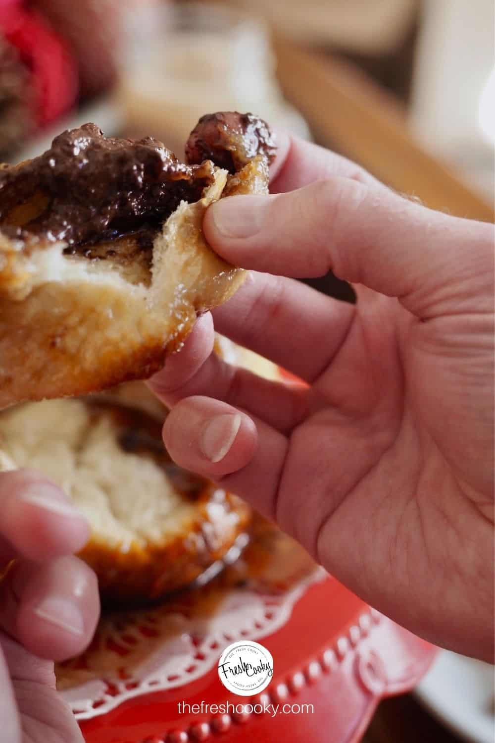 Gooey Chocolate Monkey Bread recipe with hand tearing apart a chocolate stuffed bread roll.