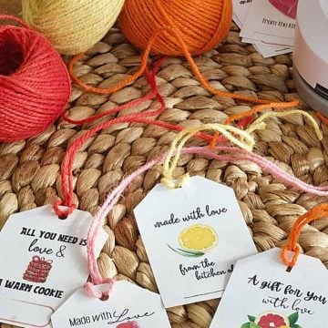 from the kitchen of gift tags on a rattan place mat with colorful spools of twine behind scissors.