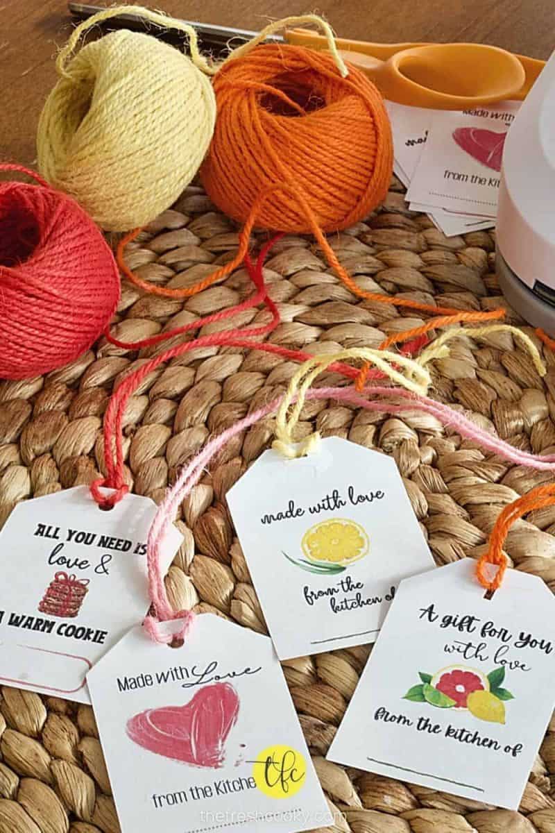 from the kitchen of gift tags on a rattan place mat with colorful spools of twine behind scissors.