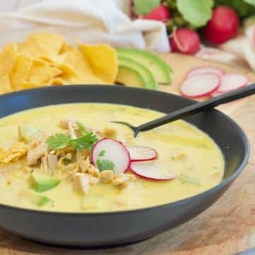 Chicken Poblano Soup recipe hero image with soup in a black bowl.