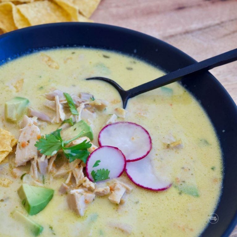 Creamy chicken poblano soup garnished with sliced radishes, tortilla chips and avocado.