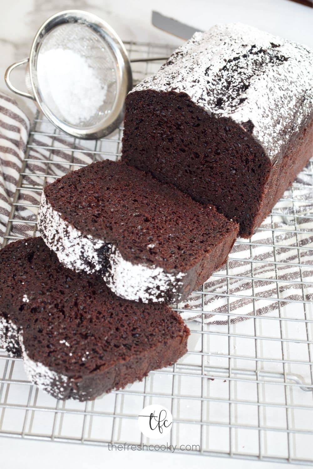 Best Easy Chocolate Loaf Cake on wire rack with powdered sugar dusting and sliced