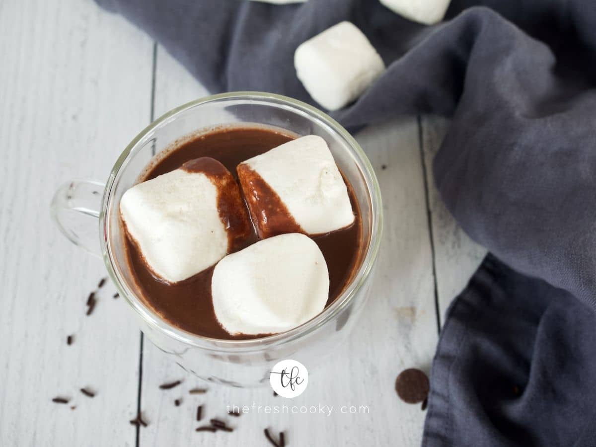 Top down shot of hot chocolate with chocolate chips, topped with three marshmallows.