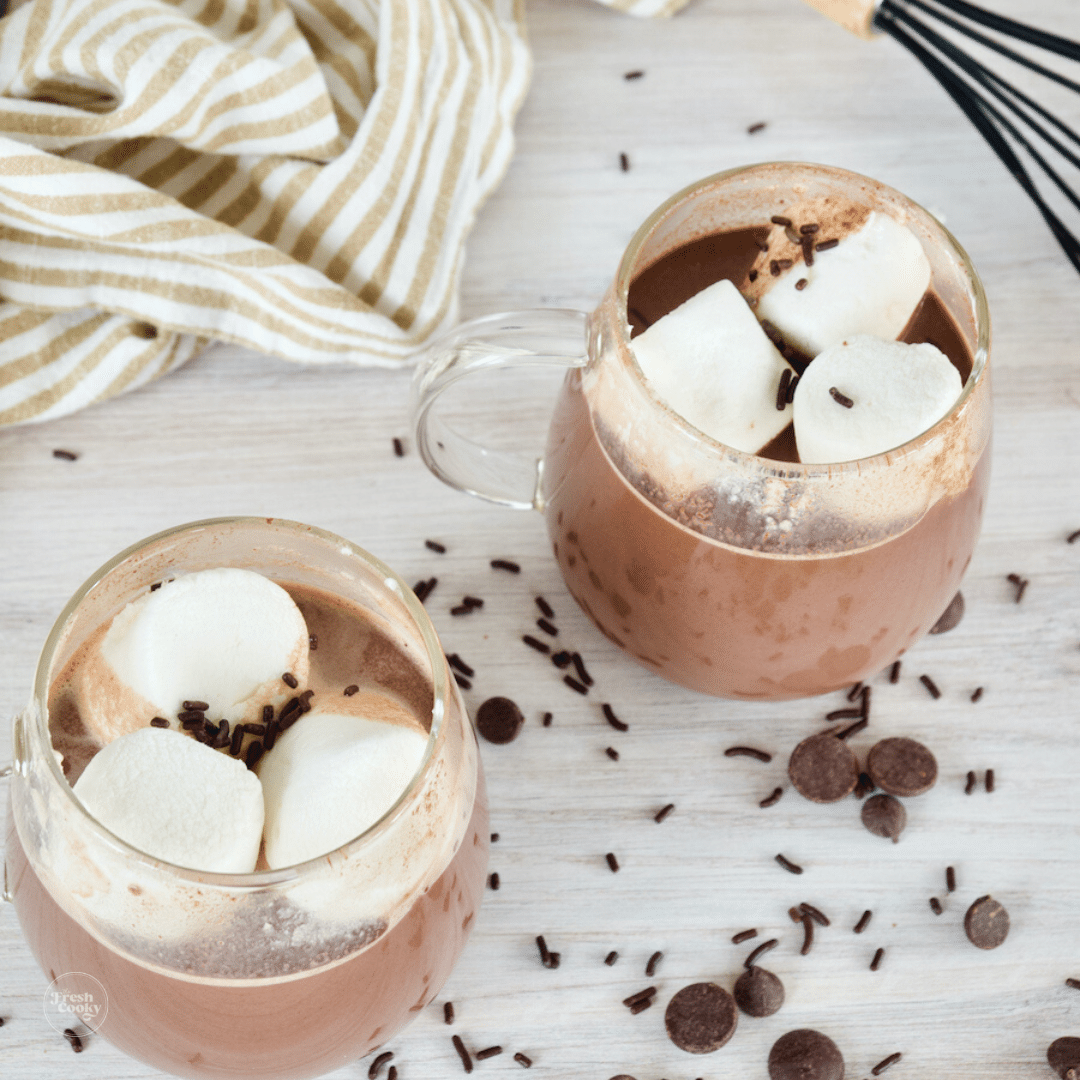 Hot chocolate in two glass mugs topped with marshmallows.