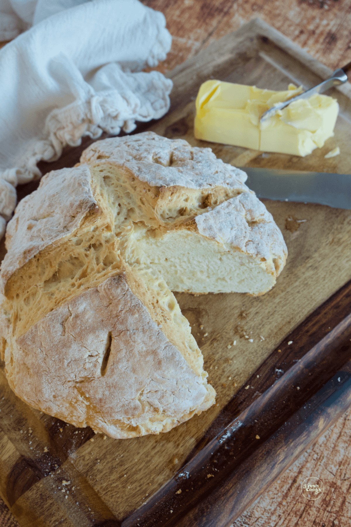 Loaf of soda bread with wedge removed, Irish butter in background.