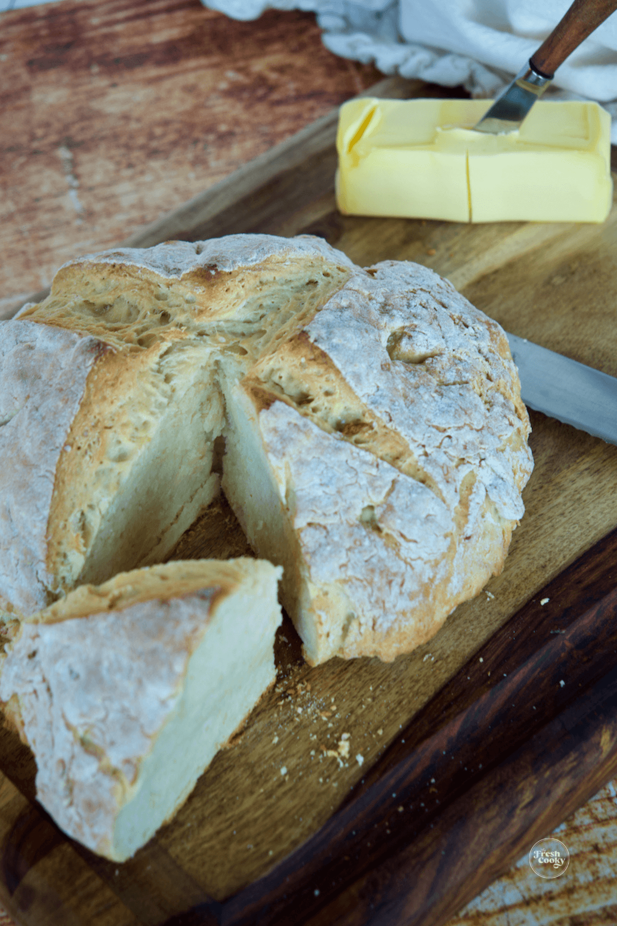 Irish soda bread on wooden cutting board, with Irish butter behind.