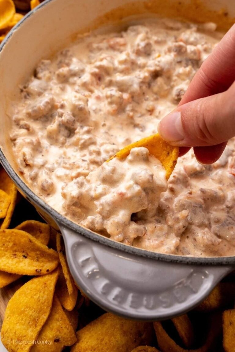 Hand diggin into the dip with a scoopable chip.