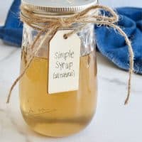A mason jar filled with a golden amber cane sugar simple syrup, tied with twine and a label.