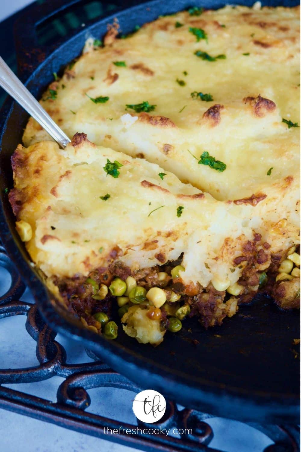 Shepherd's meat pie in a cast iron skillet with a spoon dug into the mashed potato topping.