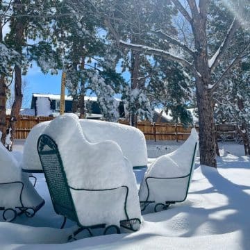 Post monster snowstorm, outdoor table and chairs with 19 inches of snow on a bright sunny day.