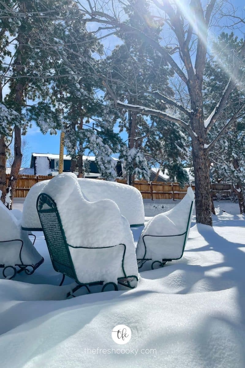 Post monster snowstorm, outdoor table and chairs with 19 inches of snow on a bright sunny day.