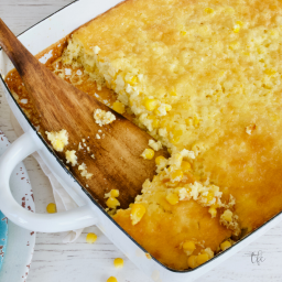 Corn pudding casserole without jiffy image of corn pudding in casserole dish with wooden spoon scooping out serving.