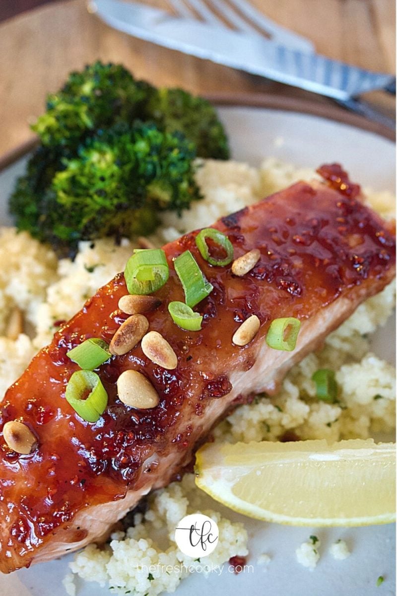 close up of raspberry glazed salmon on plate with couscous and roasted broccoli.