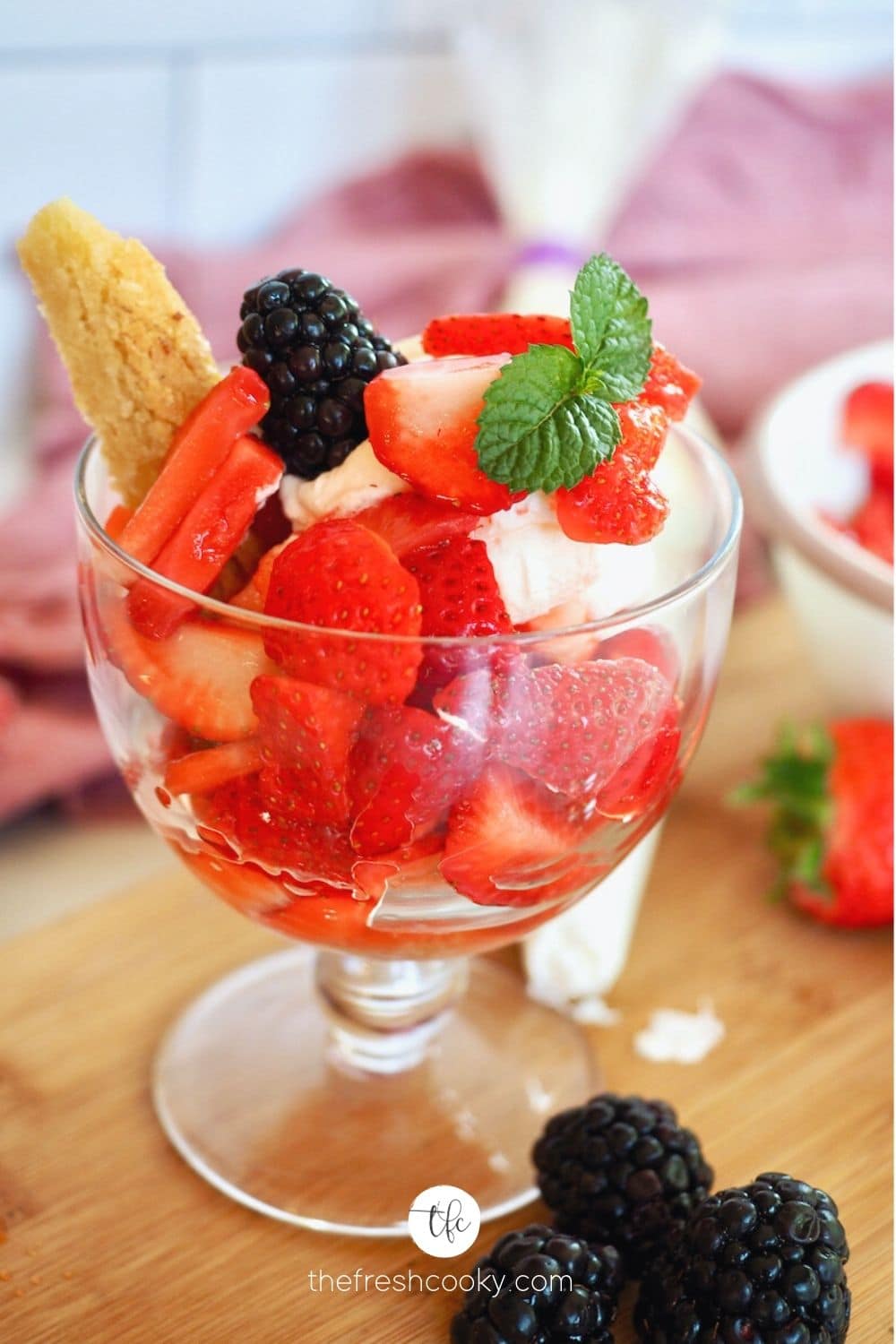 Old Fashioned Strawberry Shortcake in glass footed dish with strawberries and whipped cream, topped with mint.