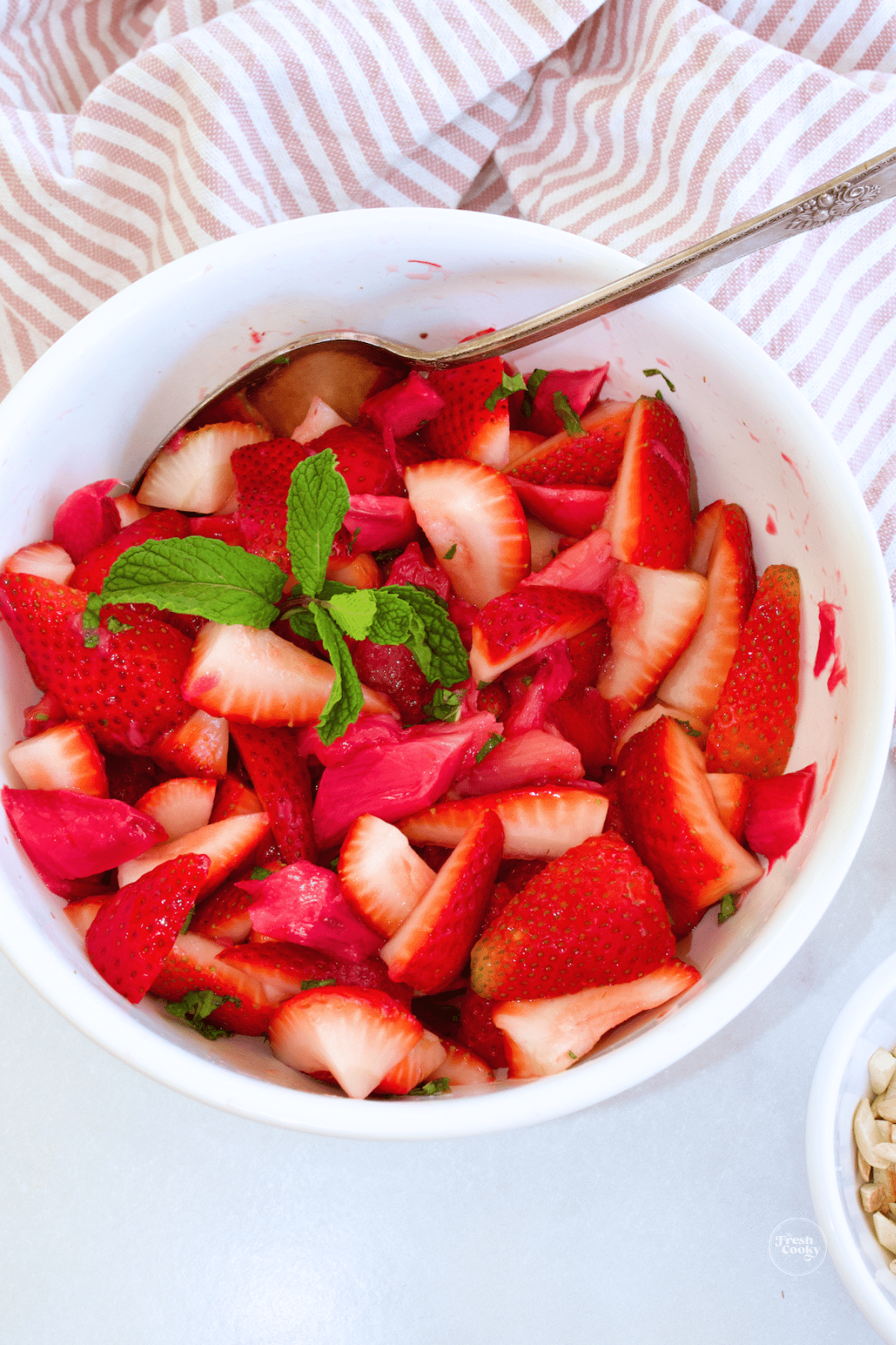 Strawberry Rhubarb Salad in a bowl with slivered almonds nearby.