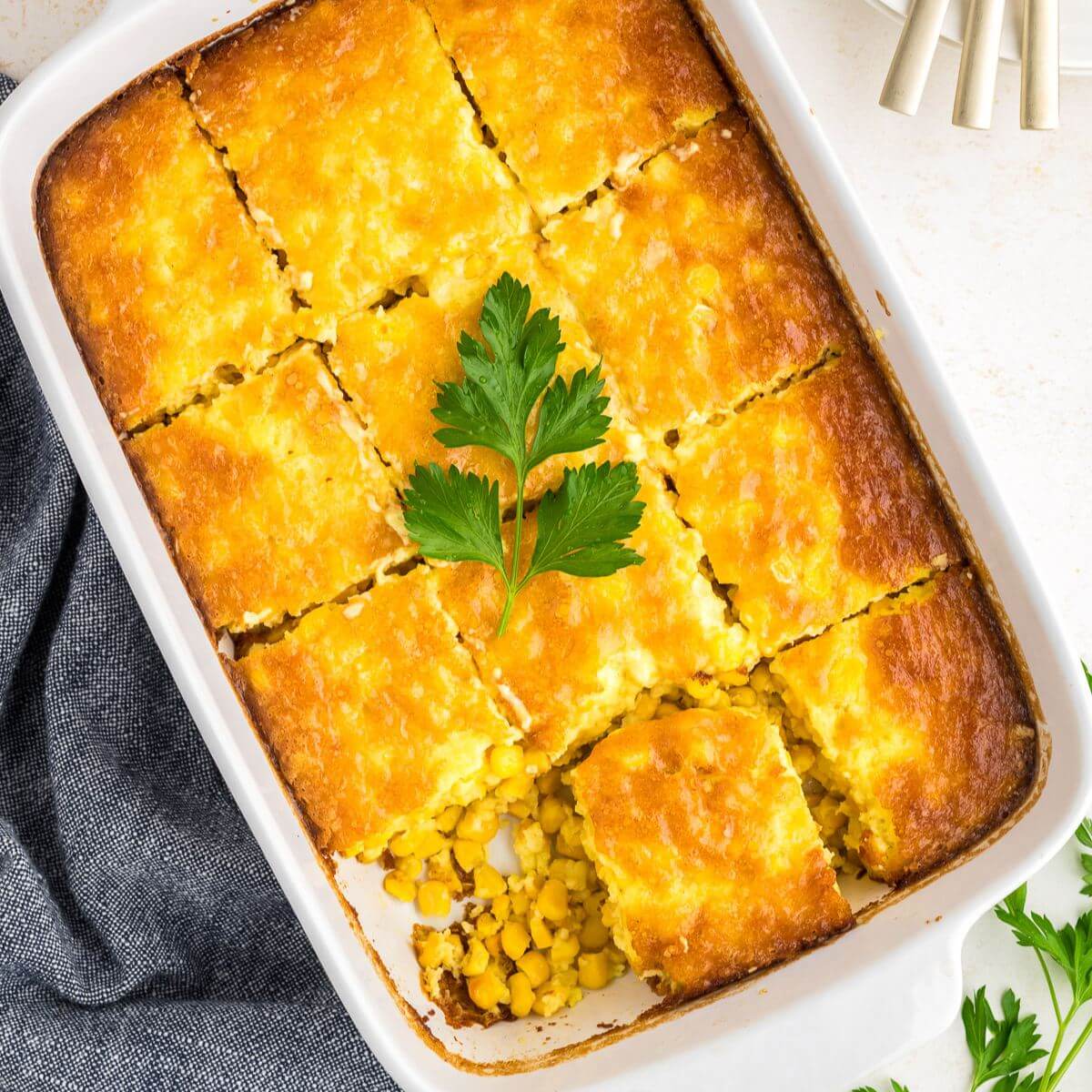 Corn pudding in a casserole dish with a piece being taken out.