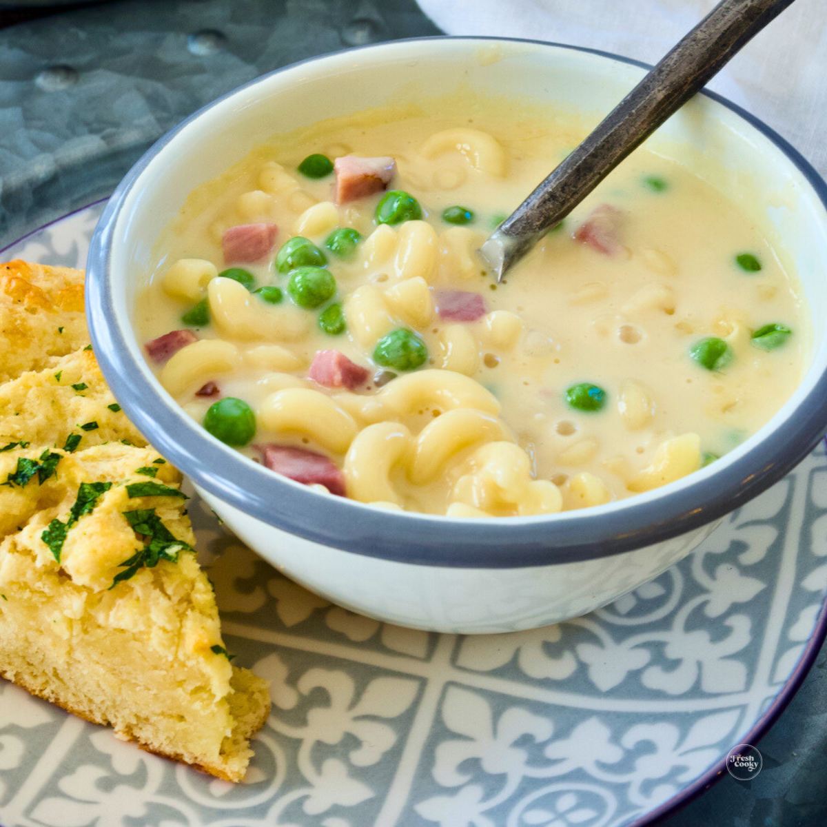 Creamy ham mac and cheese soup with fresh peas in a bowl with a serving of Red Lobster Cheddar Bay biscuits.