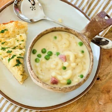 Mac and cheese soup on plate with serving of cheddar biscuit.