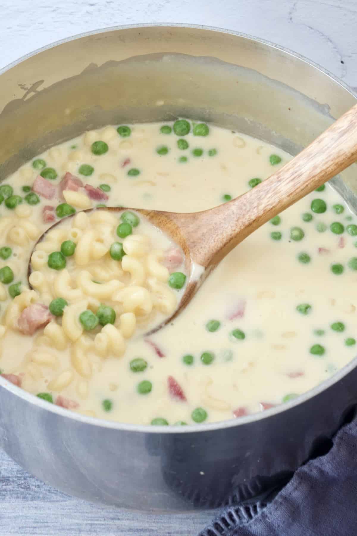 Pot full of creamy mac and cheese soup with peas and leftover ham.