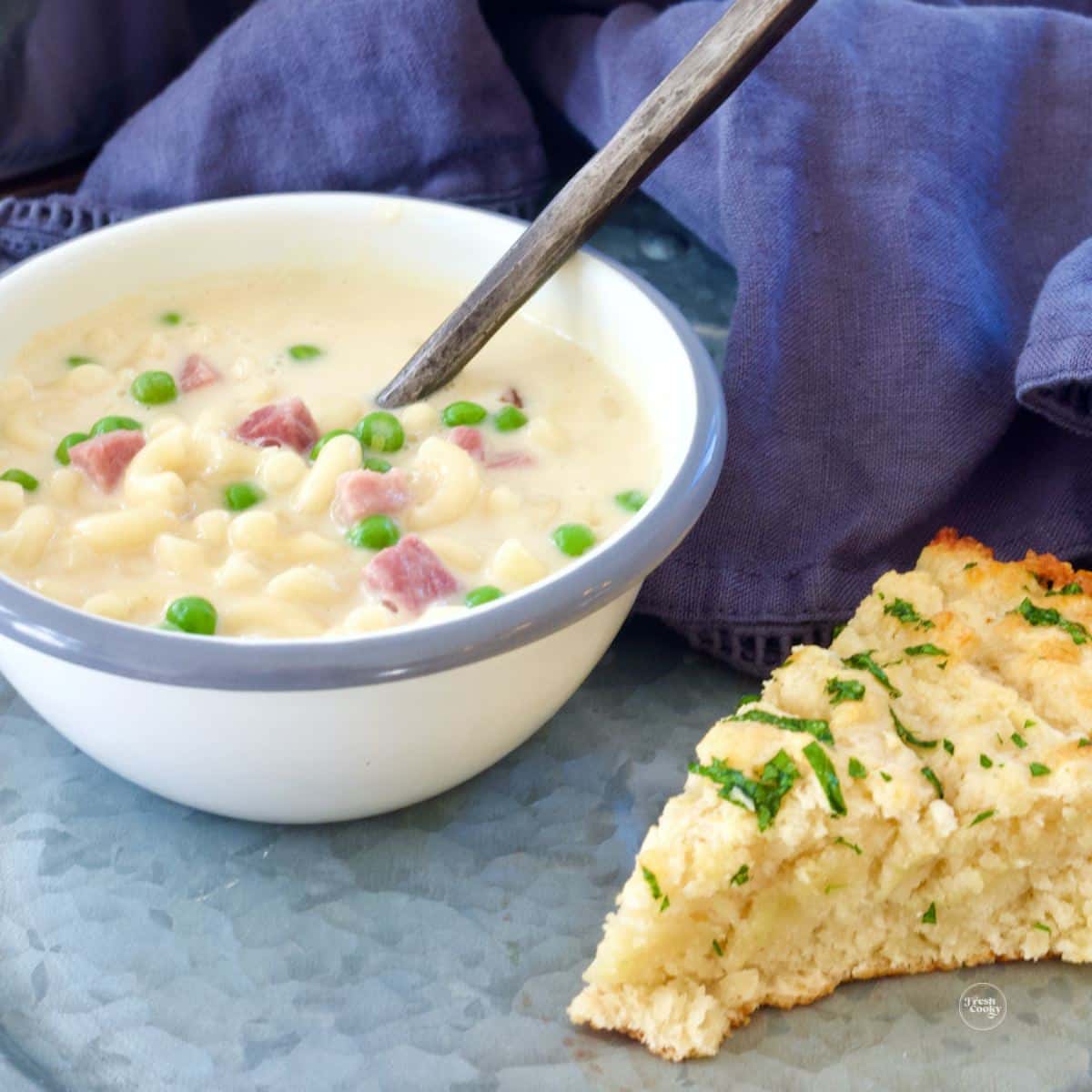 Light and creamy mac and cheese soup in a bowl served with a slice of cheddar biscuit.