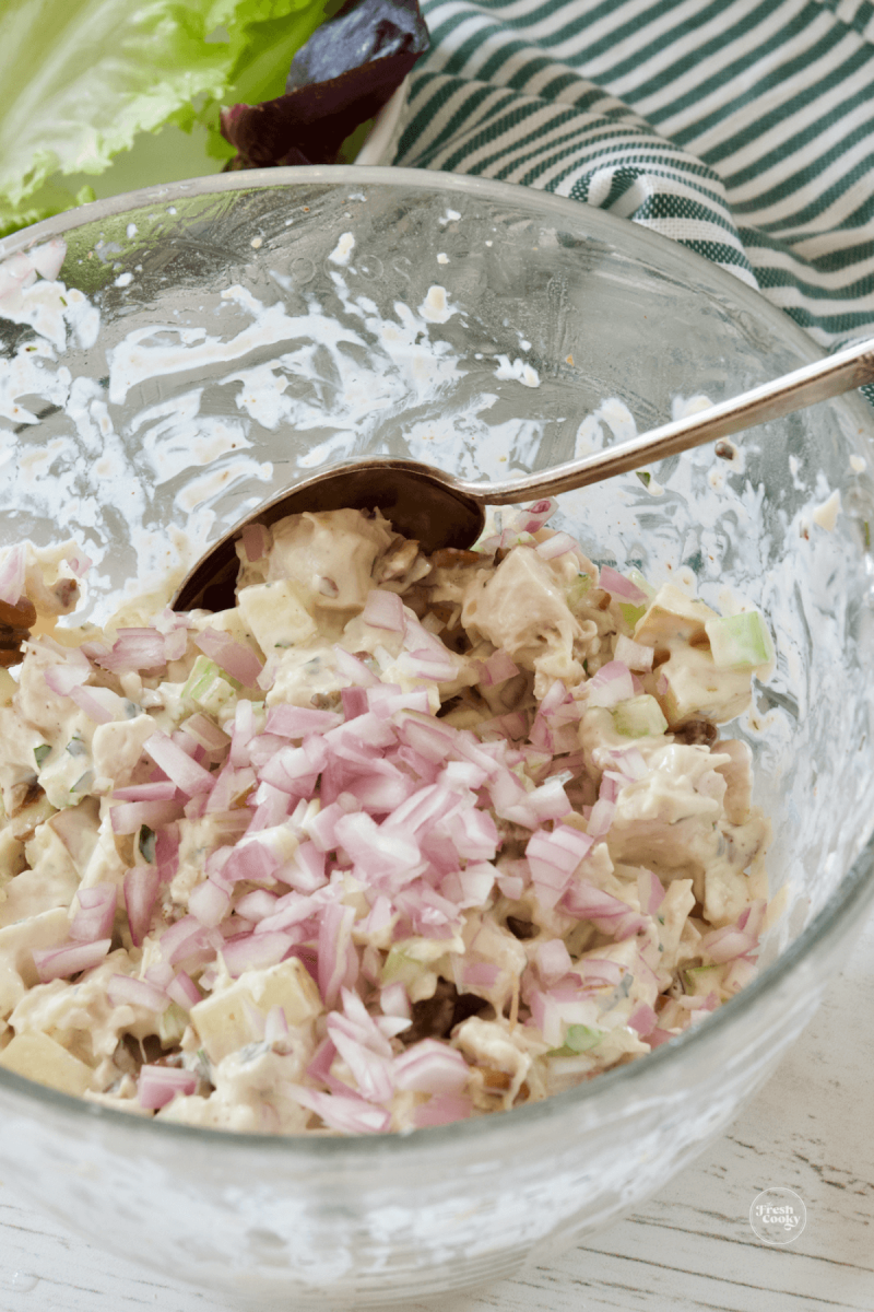 Stirring in shallots to chicken salad recipe.