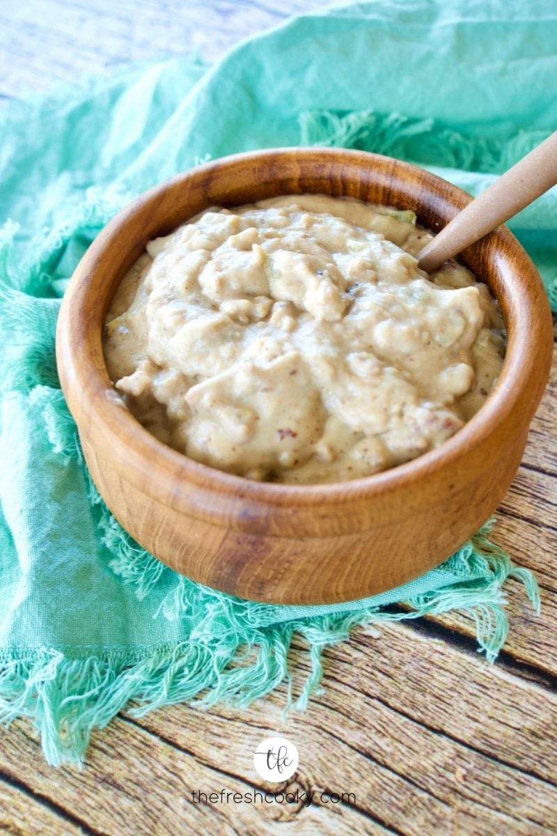 image of best green chile sausage gravy in wooden bowl with spoon on brightly colored napkin.