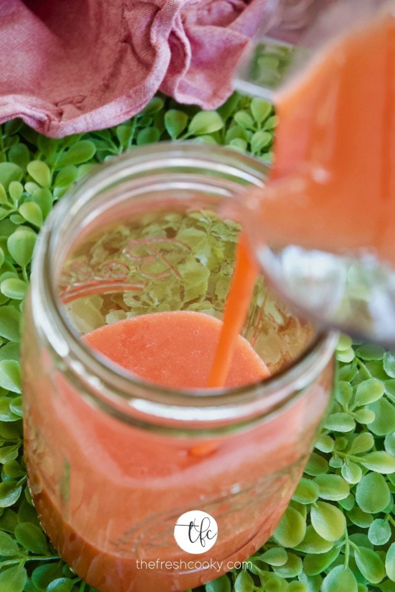 Pouring strawberry syrup into Mason Jar for storage.