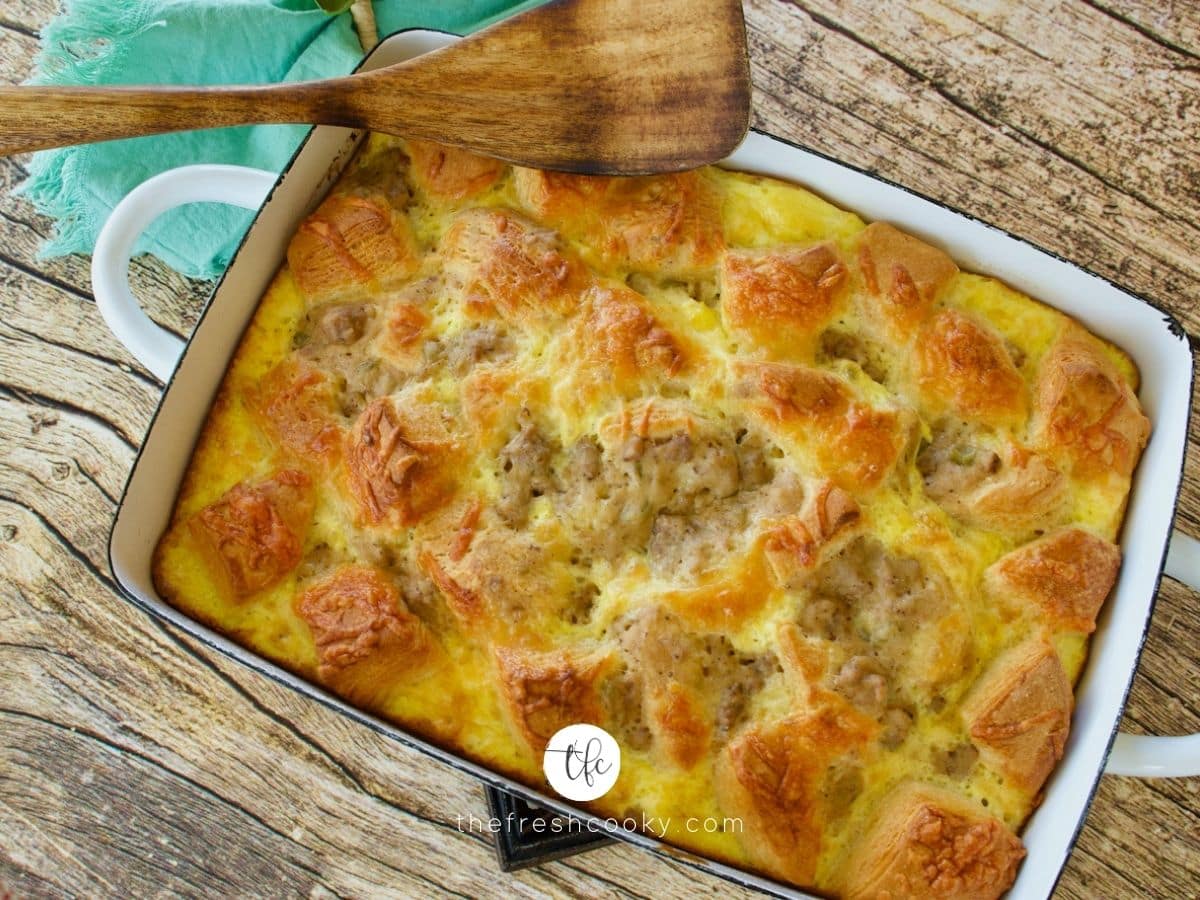 Biscuits and Gravy Casserole top down shot looking at casserole golden brown and bubbly with wooden serving spoon.