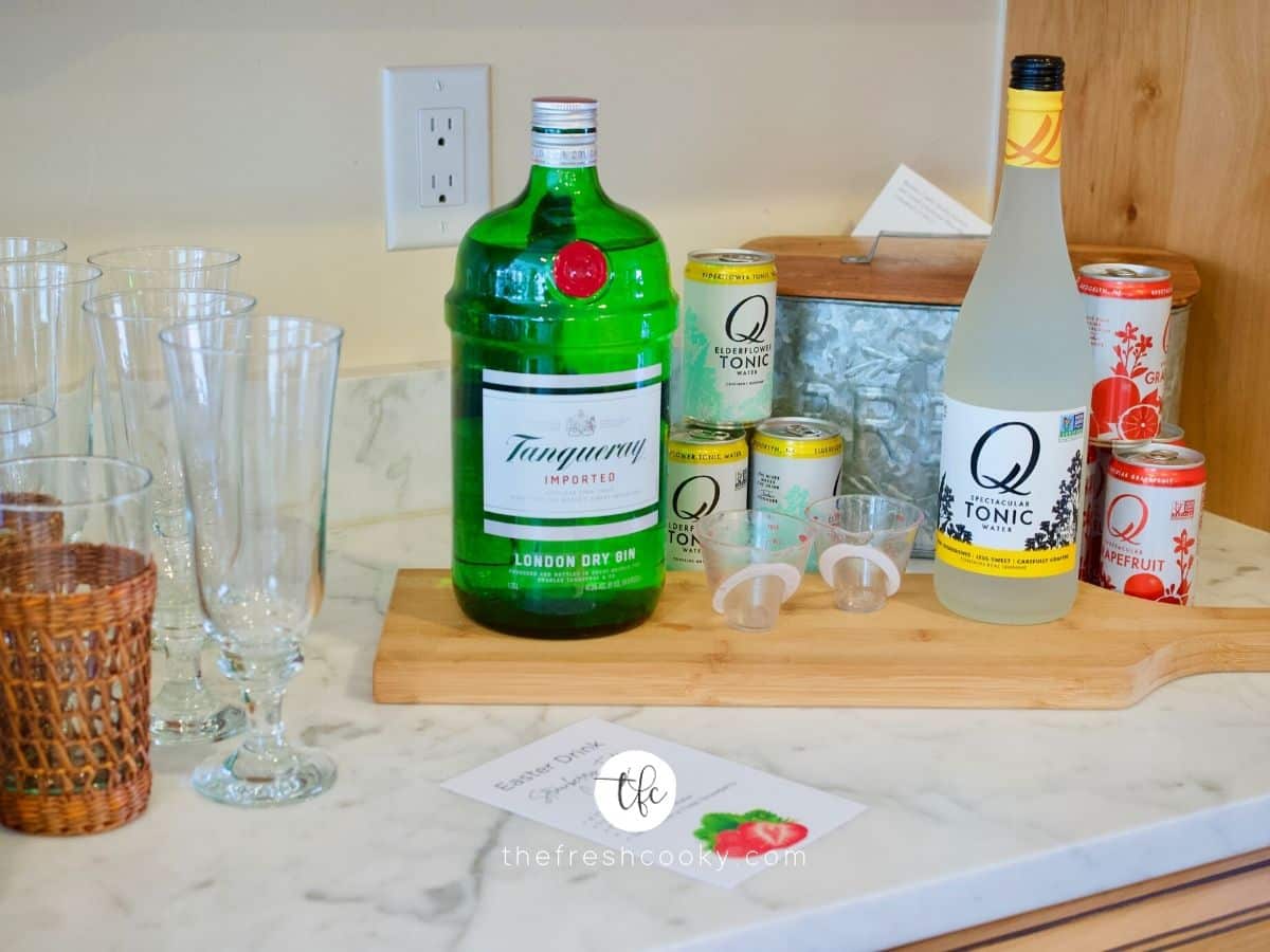 Cocktail Station set up for Strawberry Gin Cocktail. Glasses, on cutting board Gin, tonic waters, measuring cup and instructions.