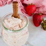 DIY Strawberry Sugar Soap Scrub in jar with strawberries behind.