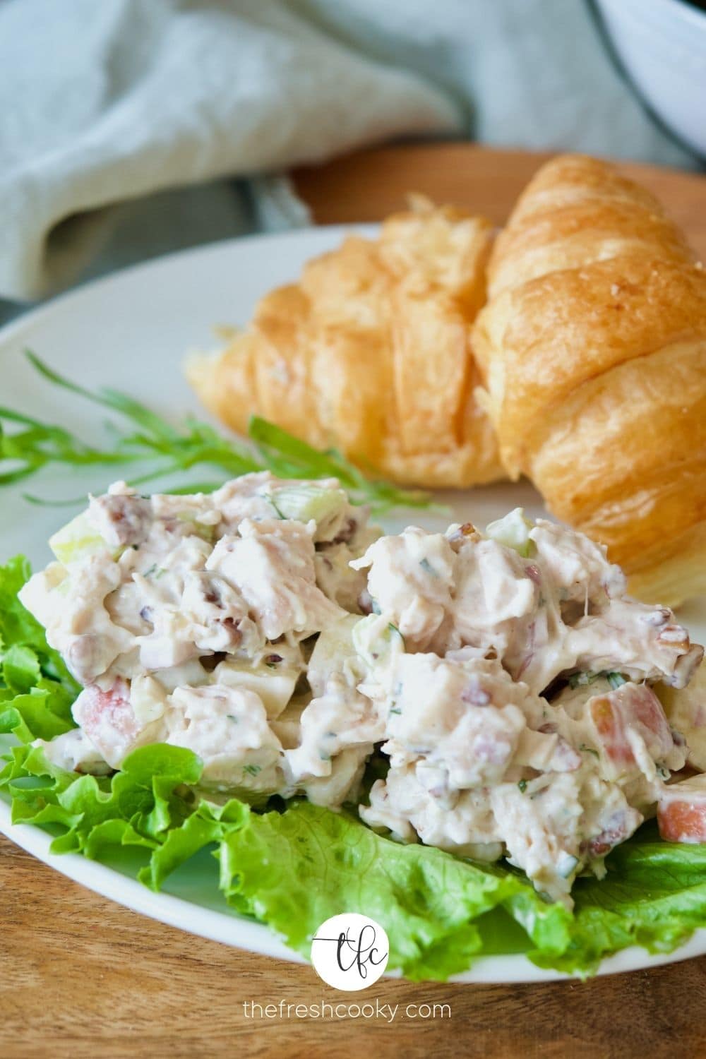 Tarragon Chicken Salad on a bed of lettuce with croissants behind.