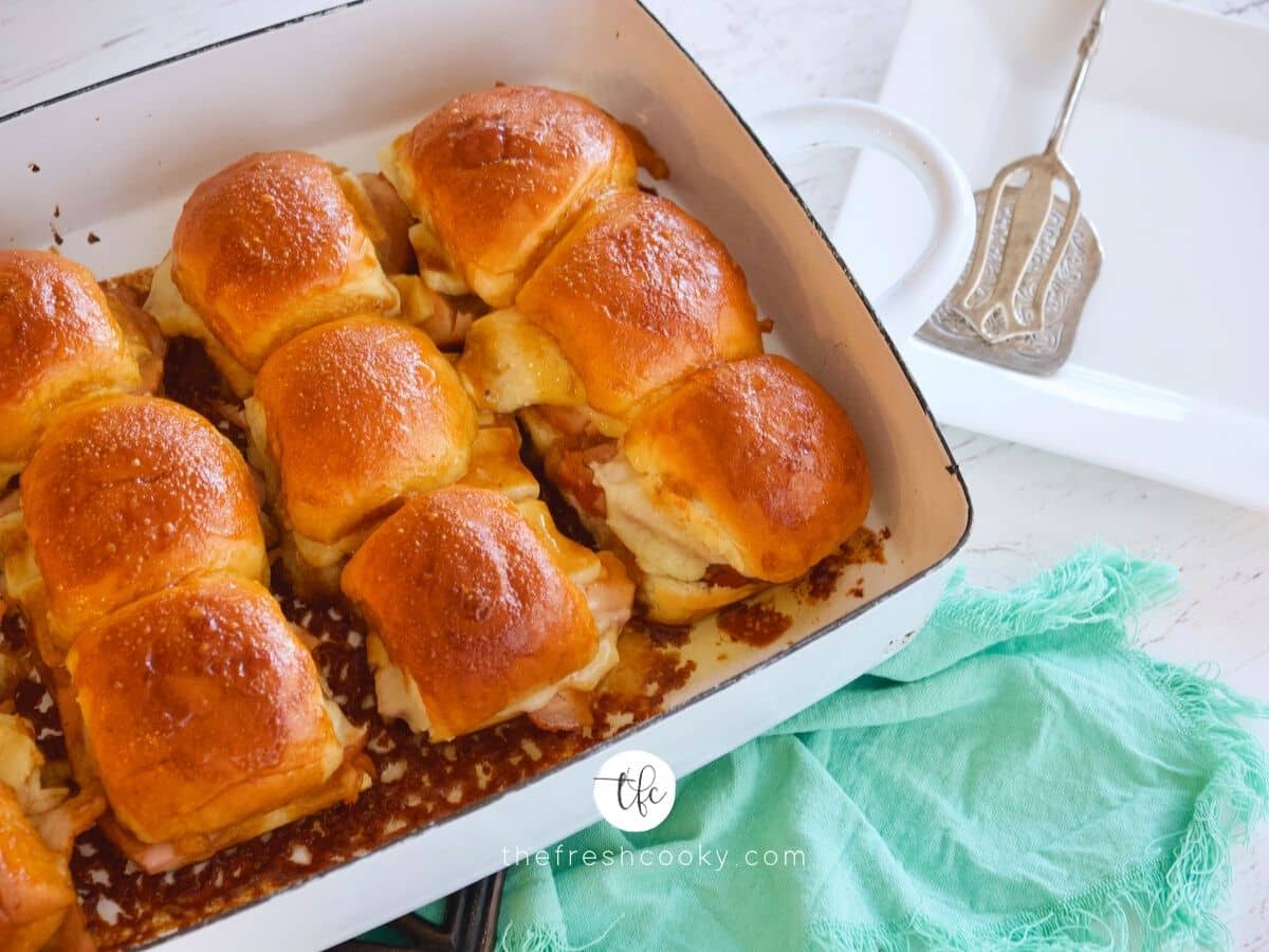 Turkey Sliders in white baking dish with plate nearby with serving utenstil.