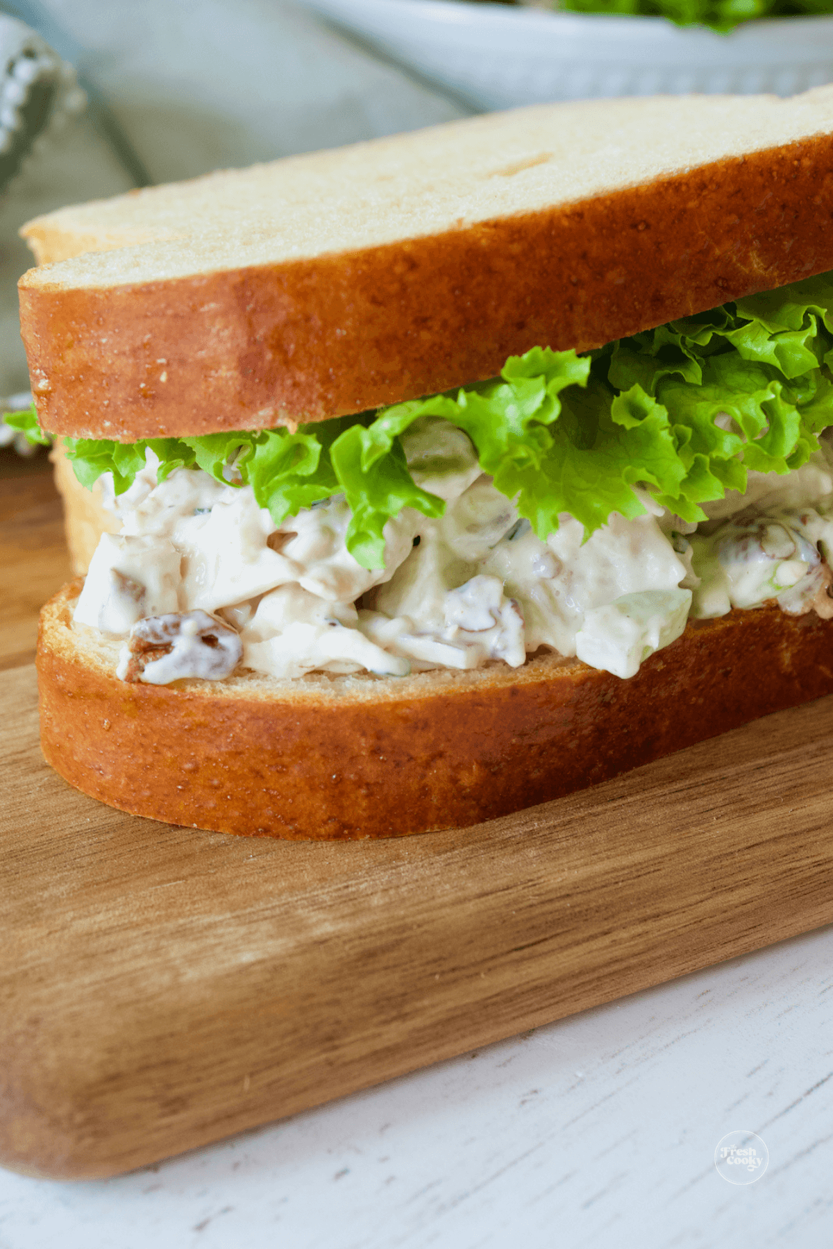 Apple pecan chicken salad on brioche sandwich bread on cutting board.