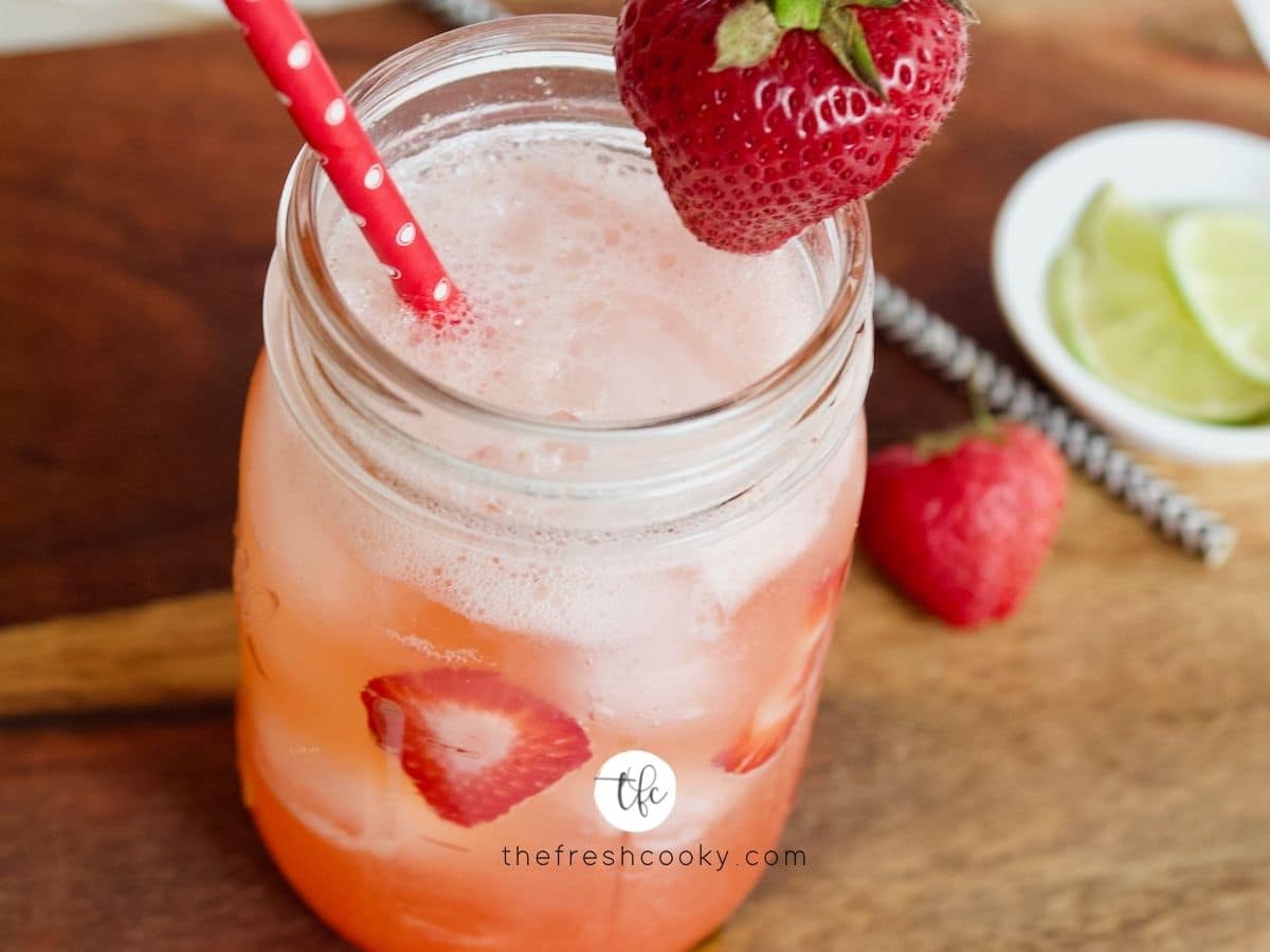 Strawberry Refresher on cutting board with strawberries around and slices of lime.