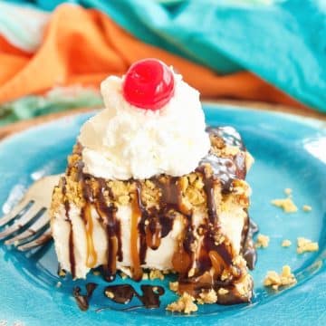Best fried ice cream cake with caramel and chocolate drizzle, whipped cream and a cherry on top, amongst brightly colored plates and napkins.