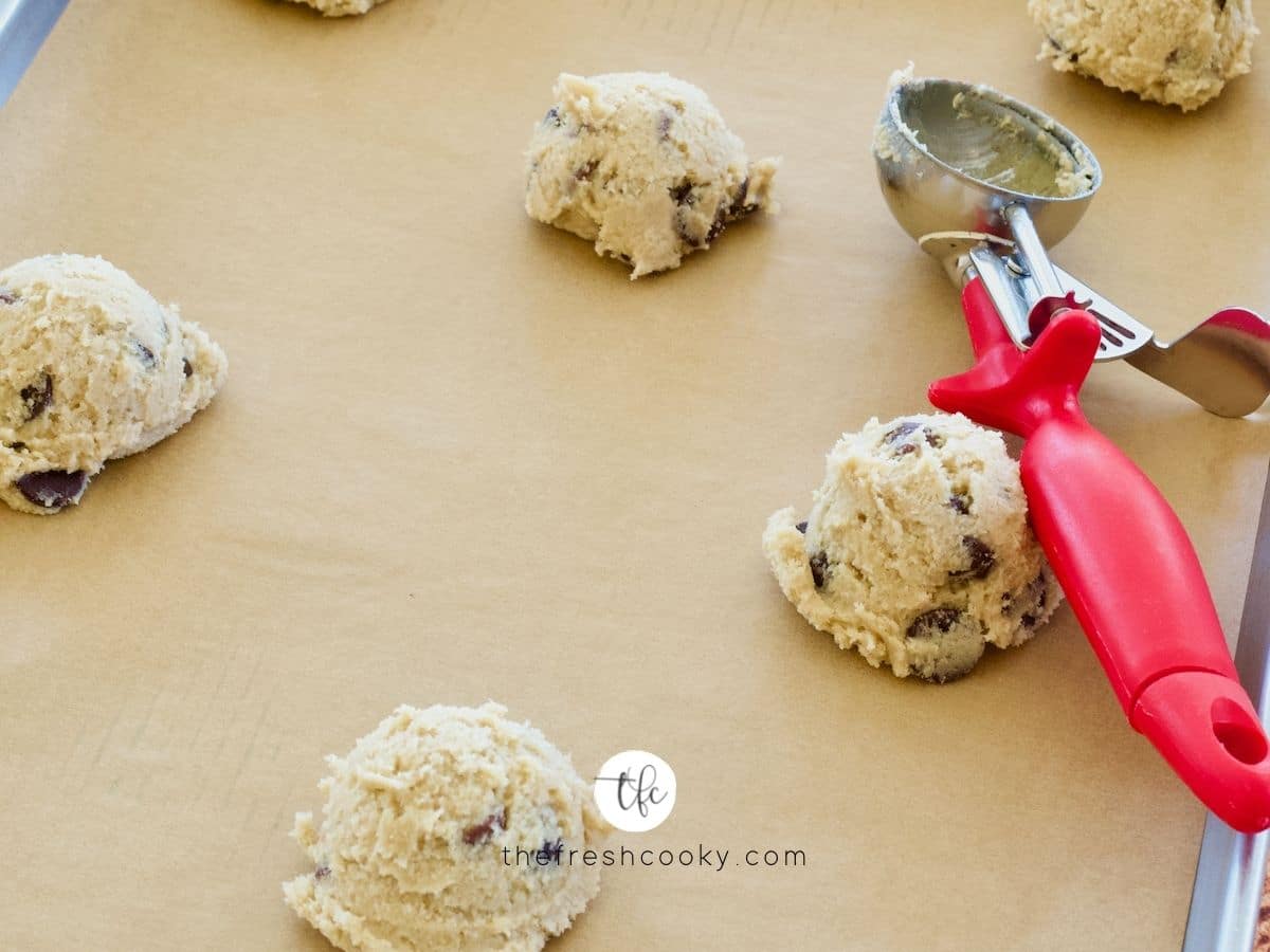 Scooping dough balls onto parchment lined cookie sheet for GF Choc Chip Cookies.