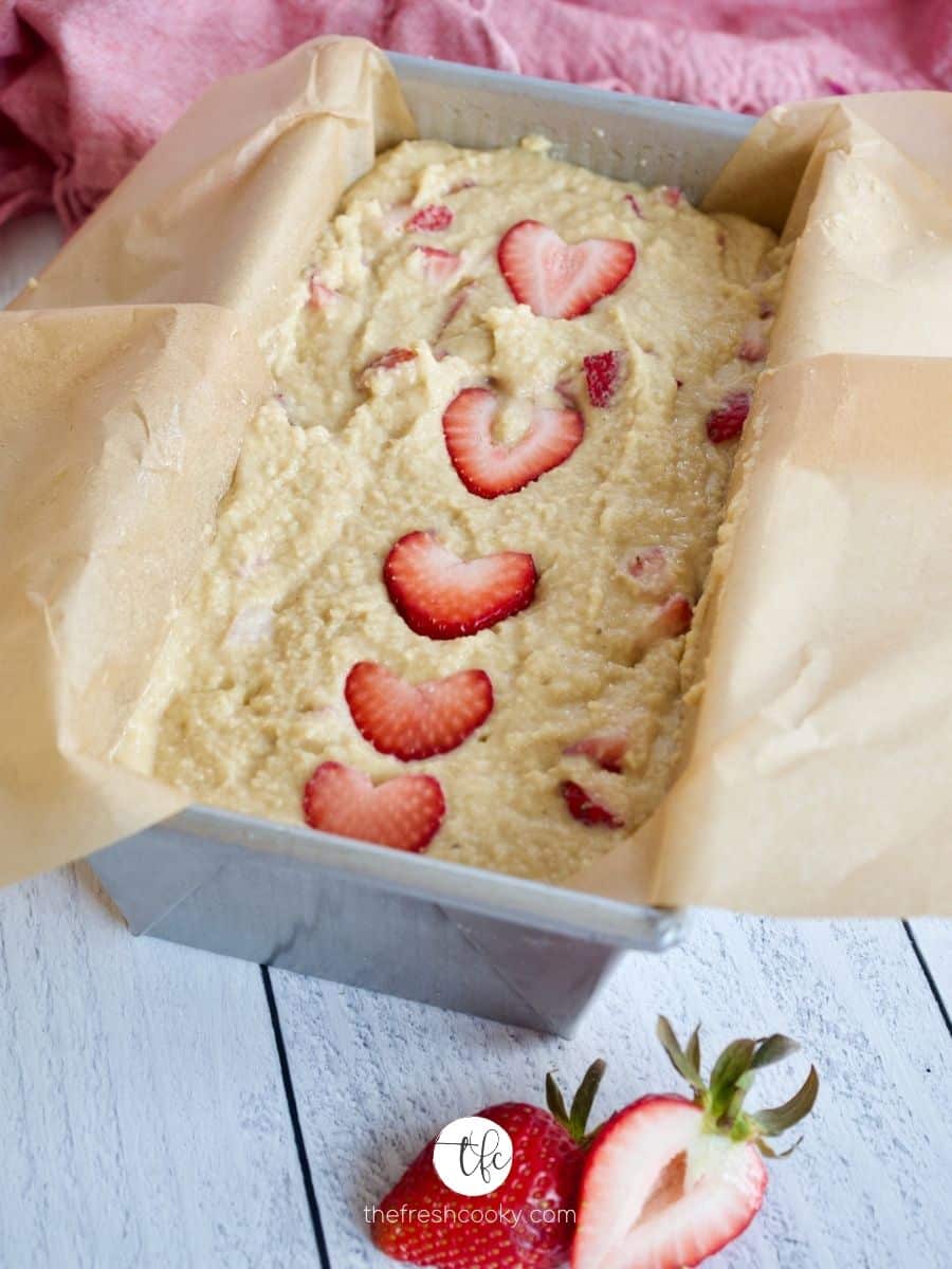 Smoothed out Strawberry Bread batter in loaf pan with sliced strawberry "hearts" on top ready for baking.