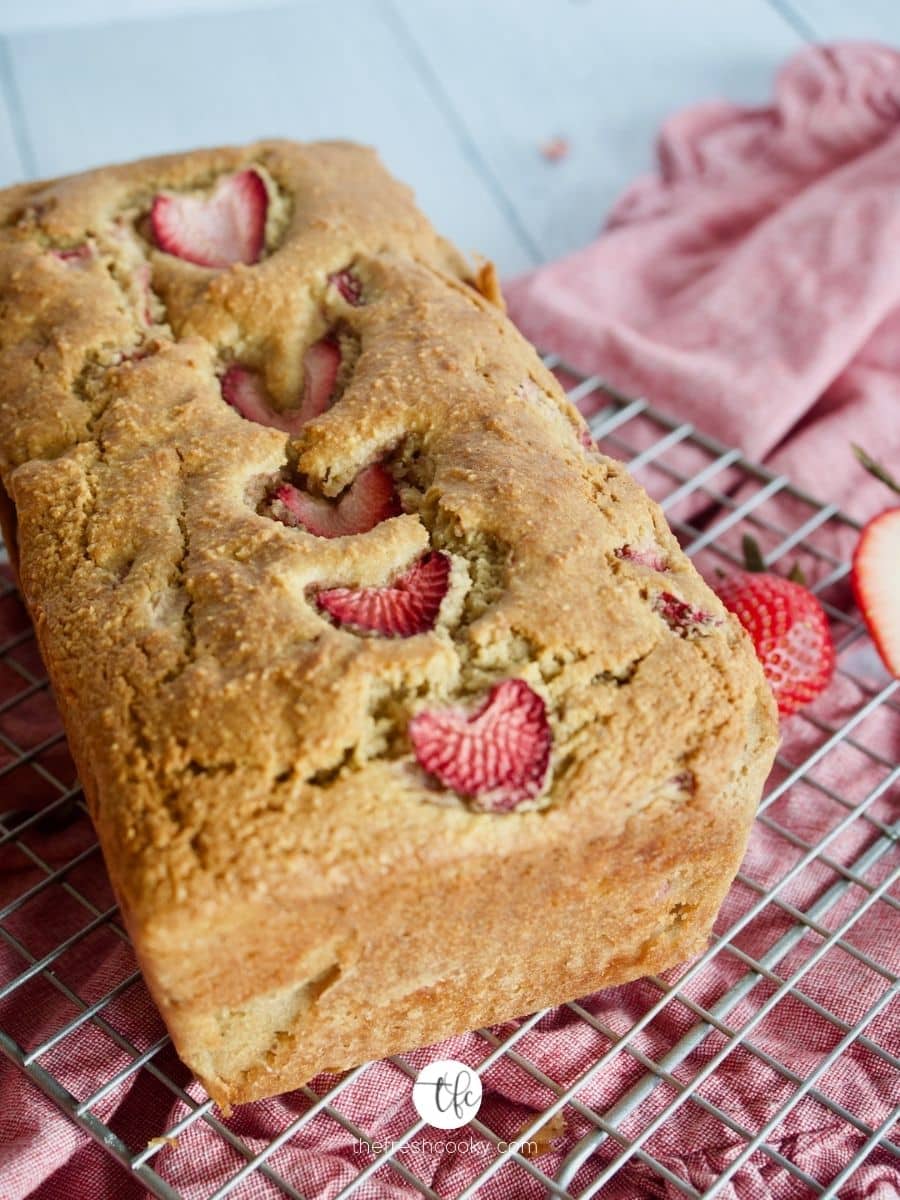 Image of gluten free, dairy free, sugar free Strawberry Quick Bread on wire rack with strawberries nearby.