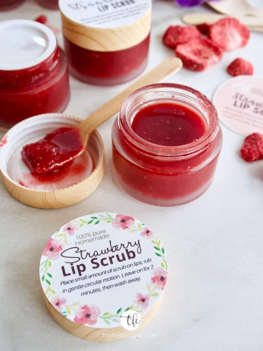 Strawberry DIY Lip Scrub in small jars with printable labels, spoonful of scrub on small wooden spoon.