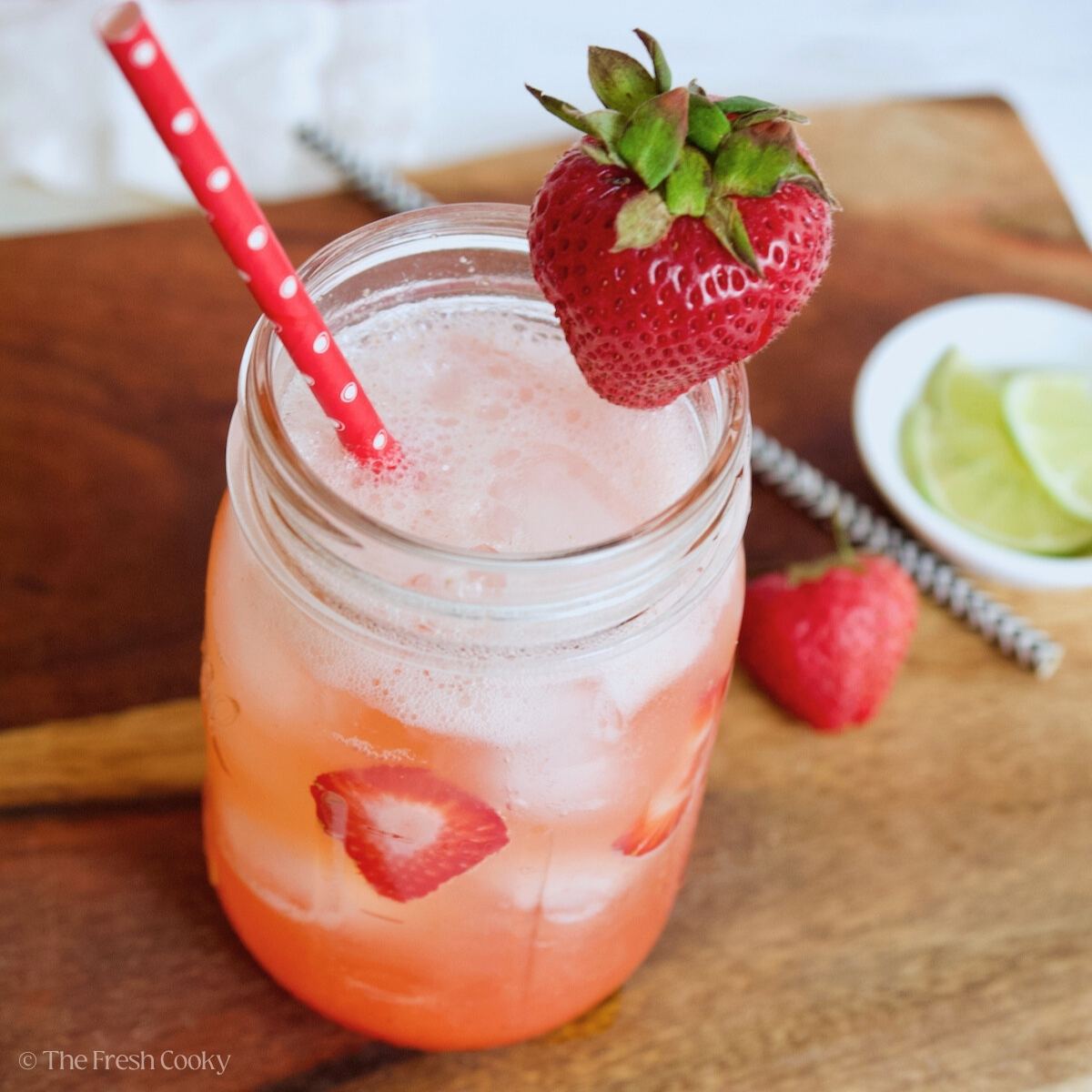 Mason jar filled with pink drink, strawberry refresher with fresh strawberries.